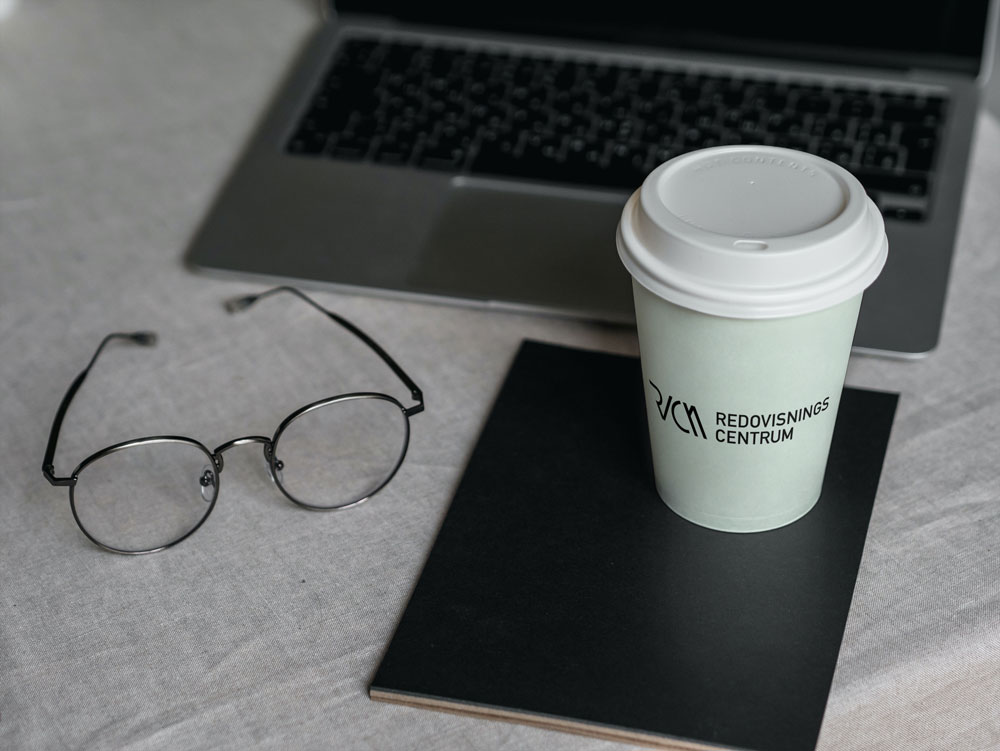 En kaffemugg och ett par glasögon framför en laptop